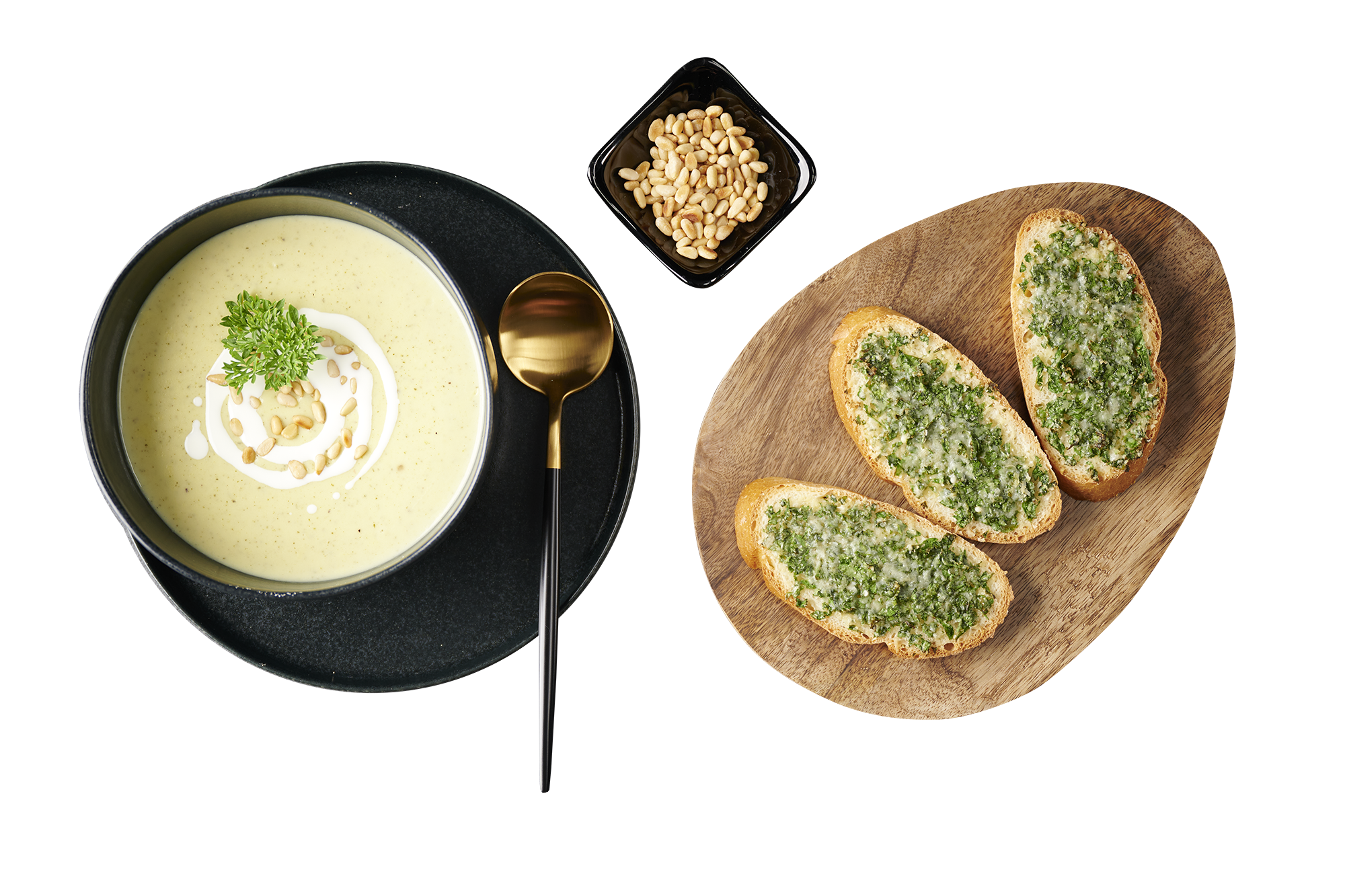 Bild zum Rezept für cremige Zucchinisuppe mit Käse-Knoblauchbaguette In schwarzem Geschirr angerichtete Zucchinisuppe, ein Schälchen mit Pinienkernen sowie ein Holzbrett mit Baguettscheiben mit Käse-Kräuter-Mischung